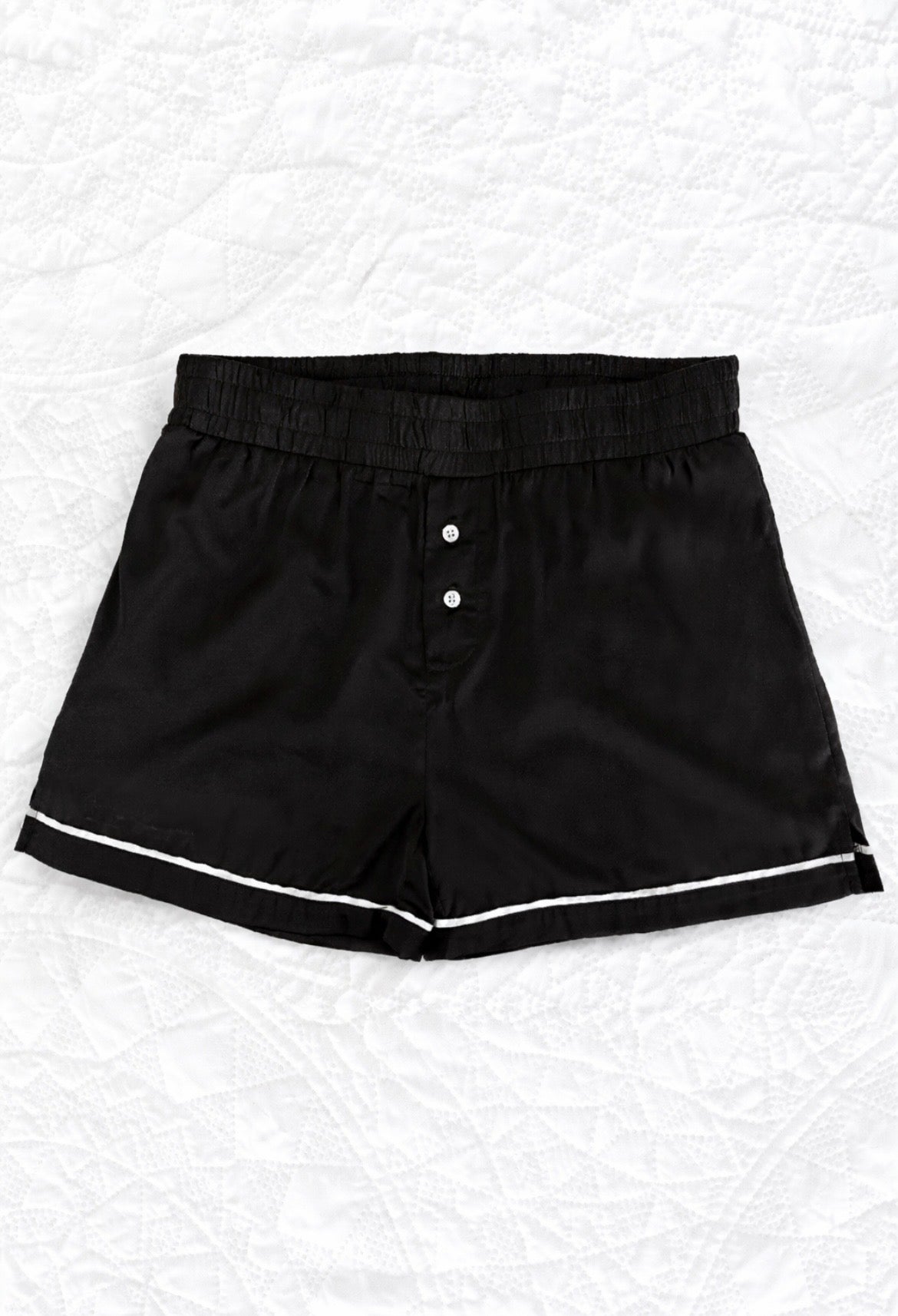 Black shorts with white trim on a textured white background
