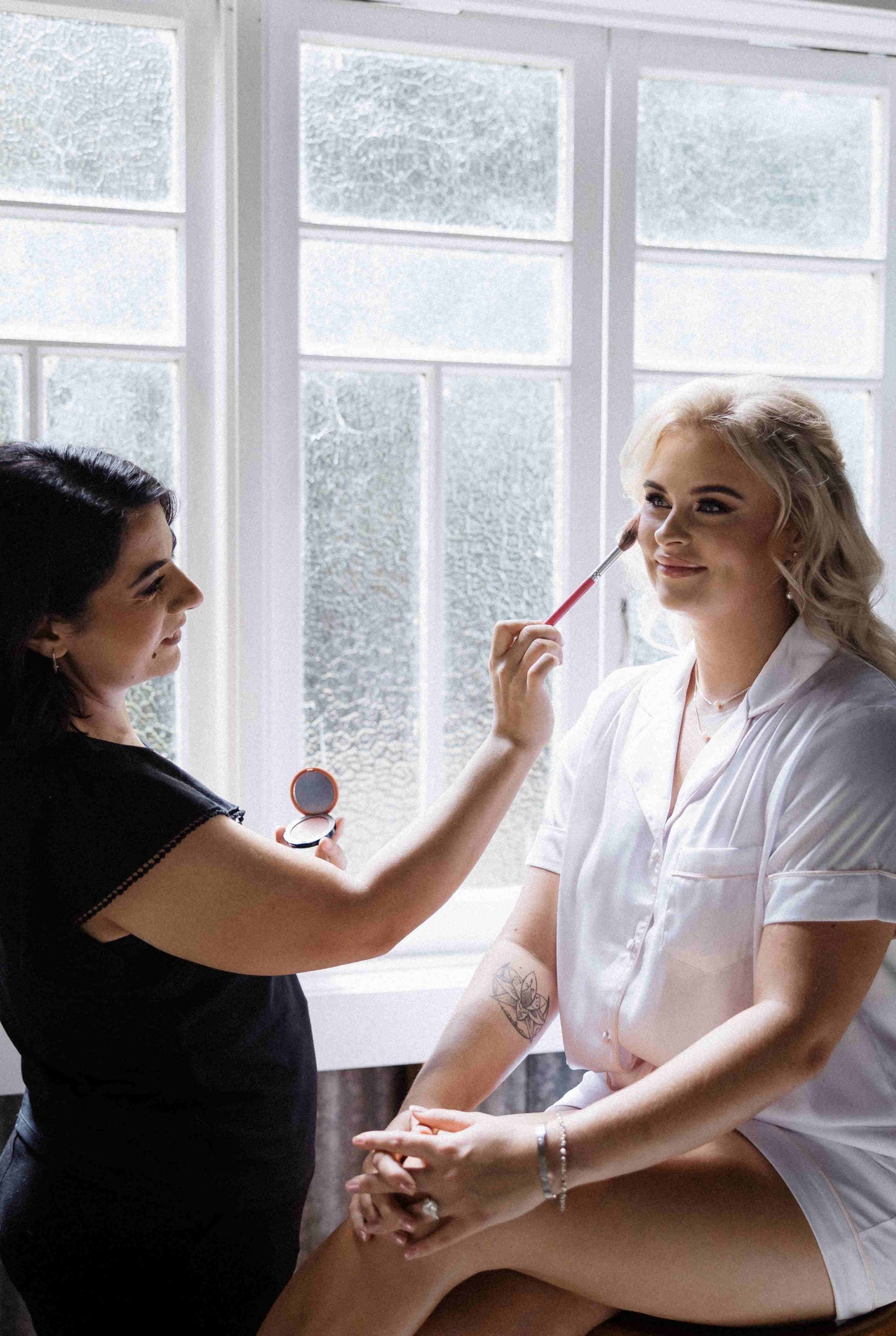 Woman relaxing indoors in white satin short pyjama set with pink trim, elegant women’s loungewear