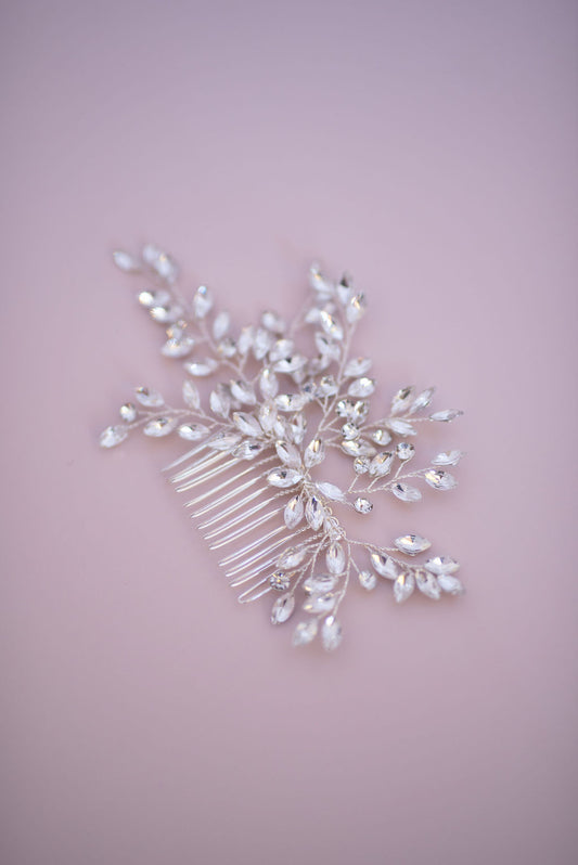 Crystal bridal hair comb displayed on soft pastel background, elegant wedding hair accessory.