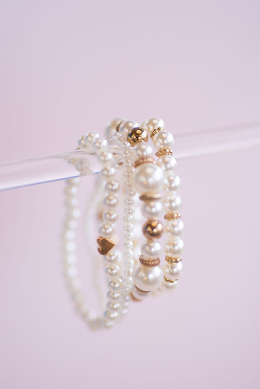 Set of four faux pearl bracelets stacked on wrist, elegant layered pearl jewellery for weddings and special occasions.