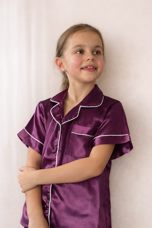 Girl wearing Luna Kids purple satin short pyjama set with white piping