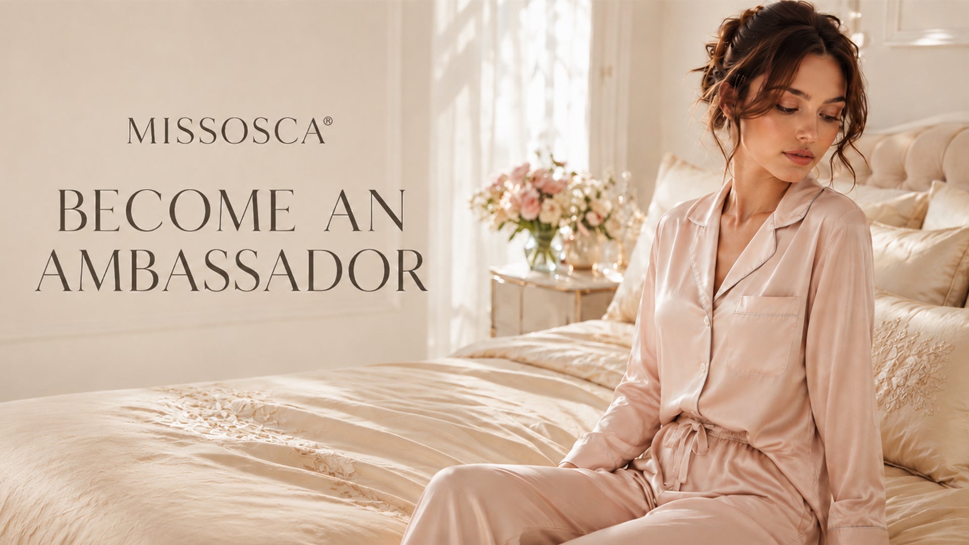 Woman in blush satin pyjamas seated on a champagne bed beside “Become an Ambassador
