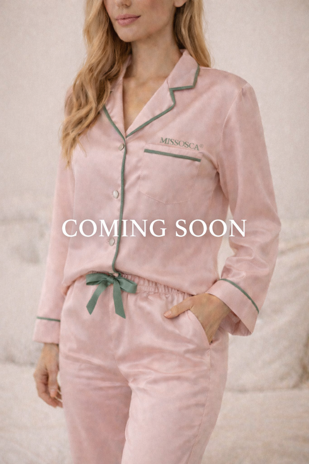 Woman wearing blush pink TENCEL™ luxury pyjama set with sage green piping and embroidered MISSOSCA® logo, “Coming Soon” text overlay