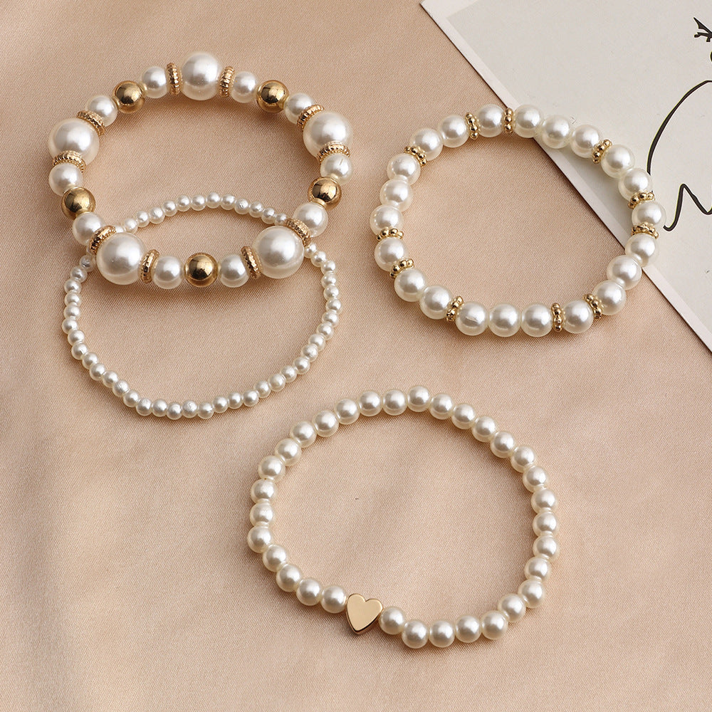 Four faux pearl bracelets arranged in flat lay, classic bridal jewellery set with elegant beaded design.