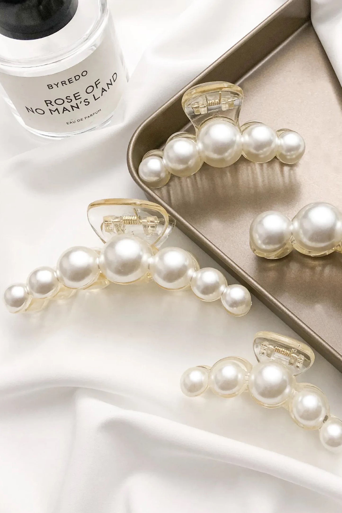 Set of elegant faux pearl hair clips styled on soft fabric, bridal and formal hair accessories.