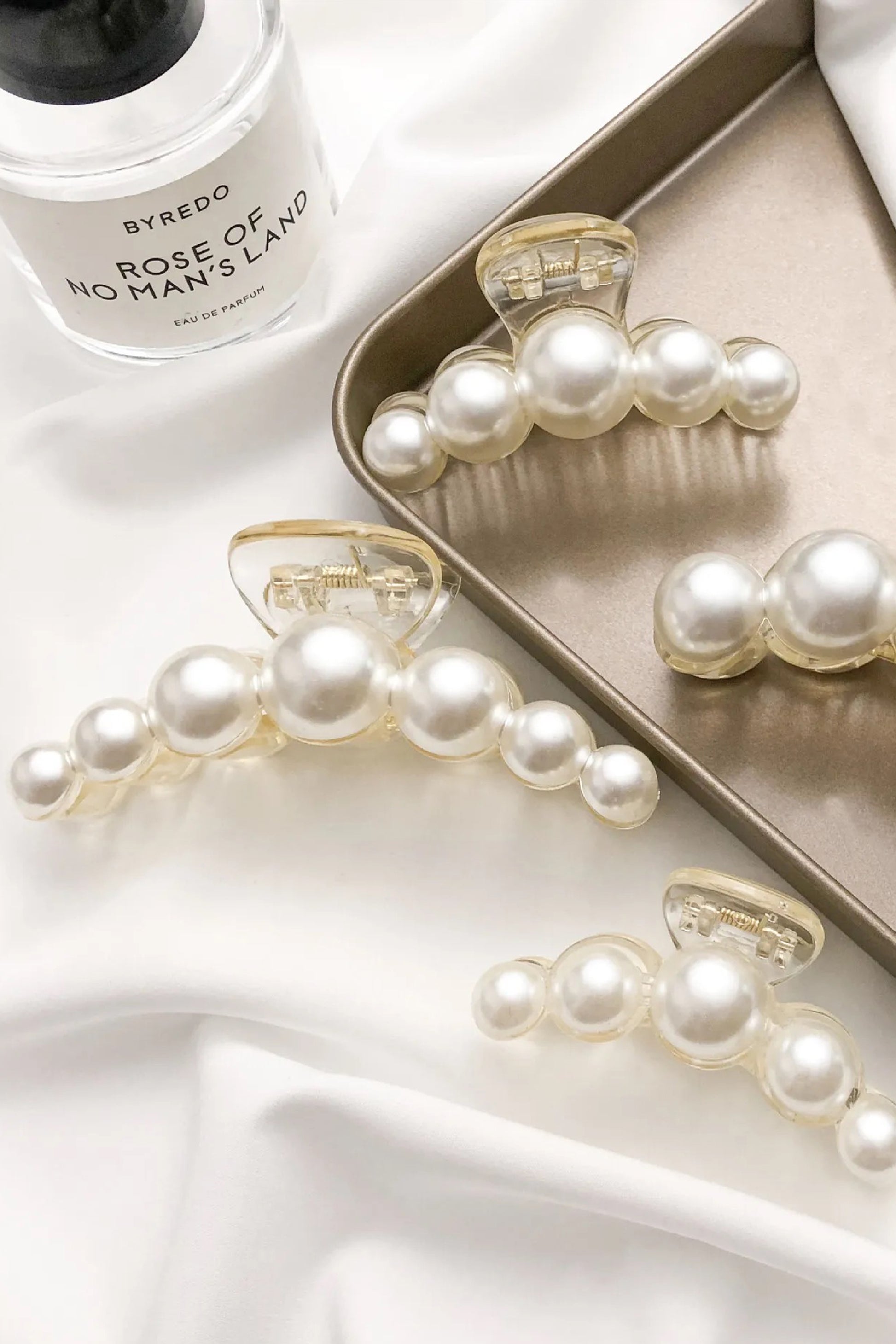 Set of elegant faux pearl hair clips styled on soft fabric, bridal and formal hair accessories.