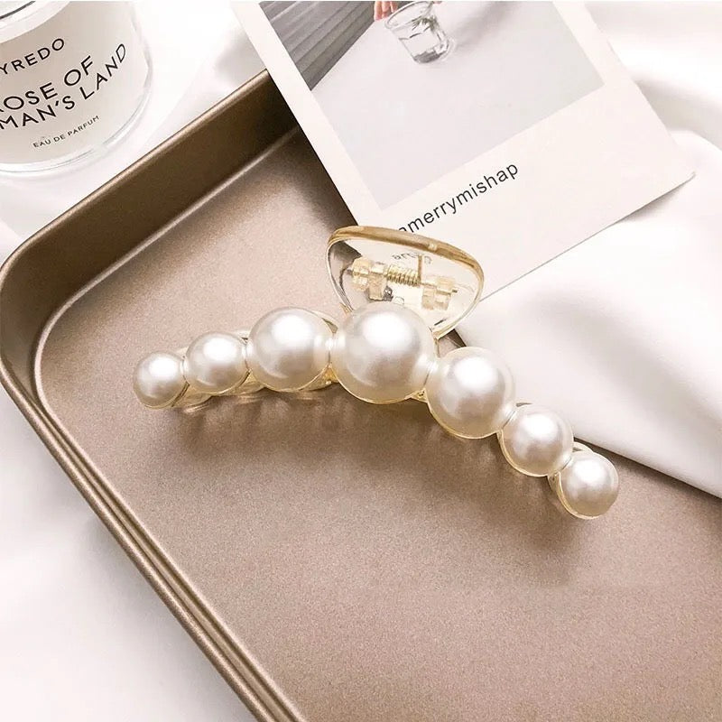 Close-up of pearl hair clips with glossy faux pearls arranged neatly in styling tray.