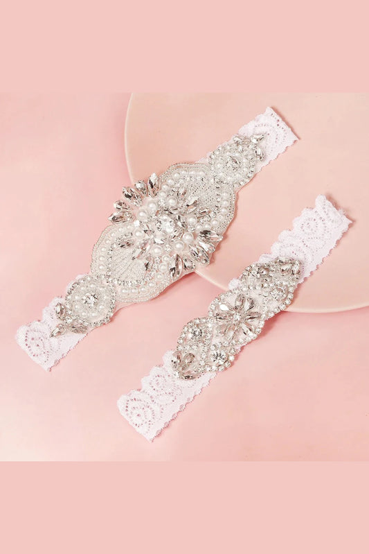 Bridal garter set with pearl and diamante detailing displayed on soft pink background, elegant wedding accessory.