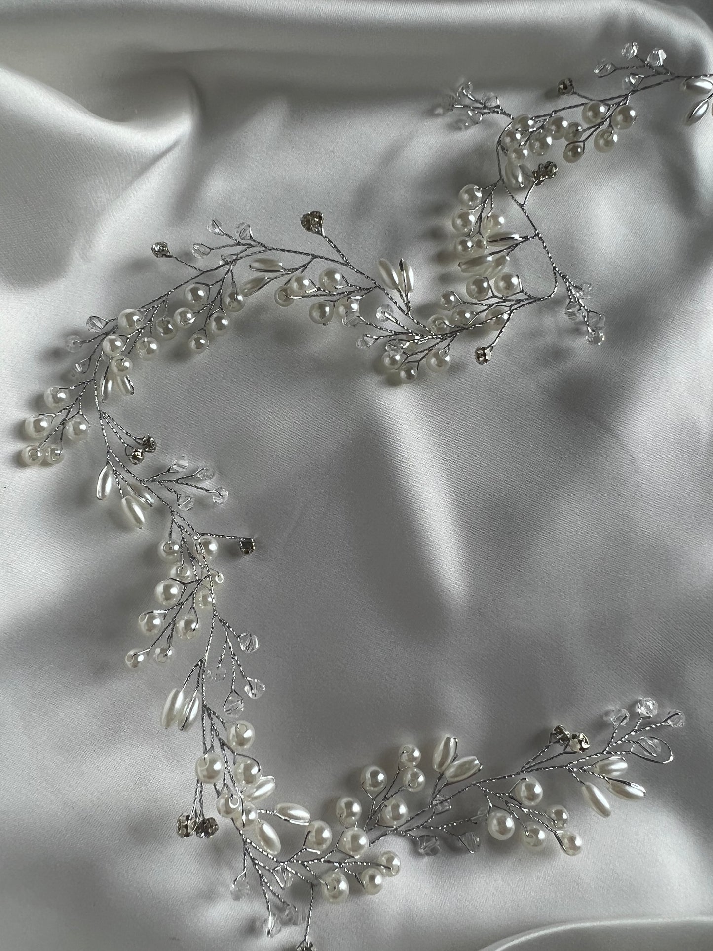 Close-up of silver bridal hair vine showing delicate crystal detailing on soft fabric.