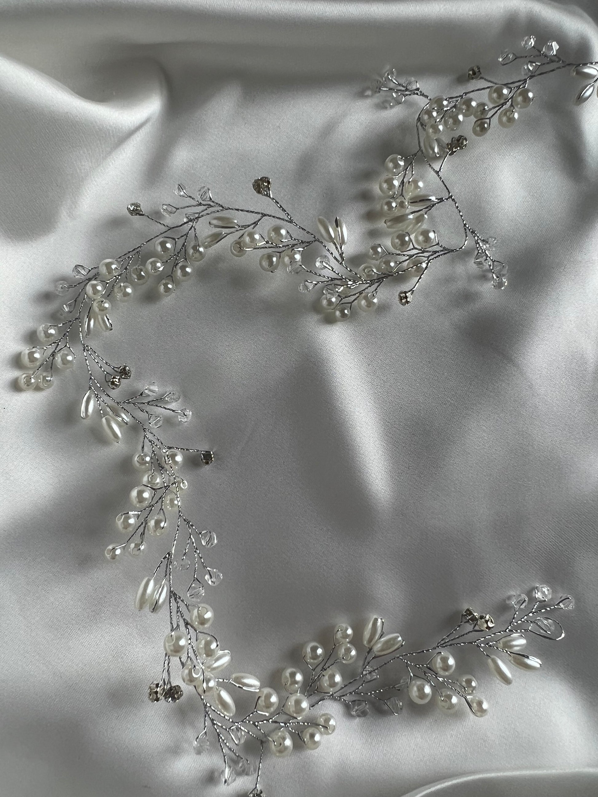 Close-up of silver bridal hair vine showing delicate crystal detailing on soft fabric.